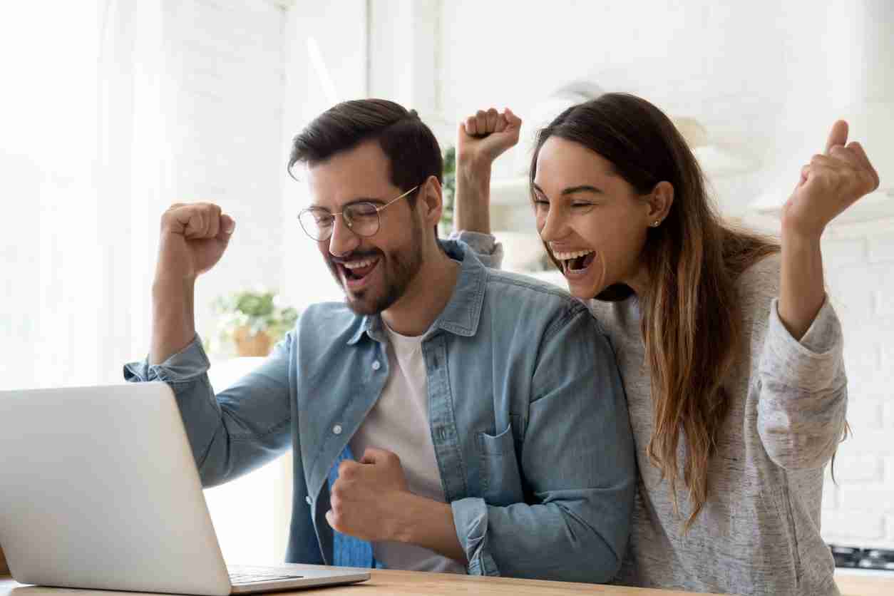 Excited young couple using laptop celebrates sml