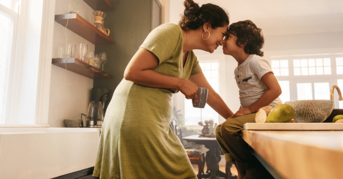 Affectionate mother touching noses with her young son in the kitchen. Cheerful mother and son looking at each other fondly.