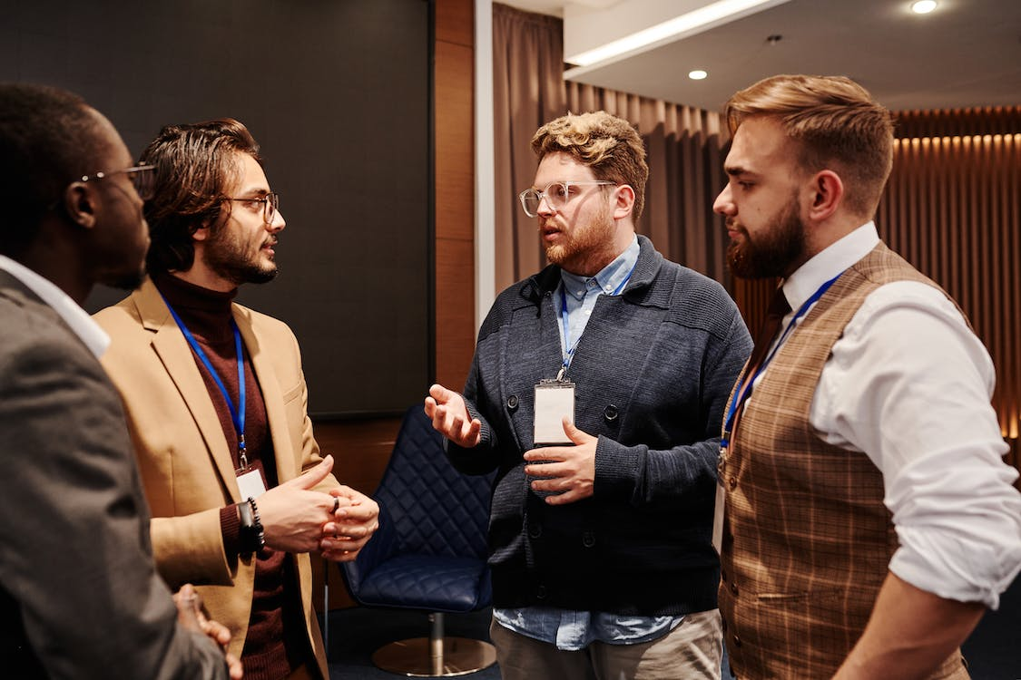 Four Men Wearing Lanyards Having a Conversation at a Conference
